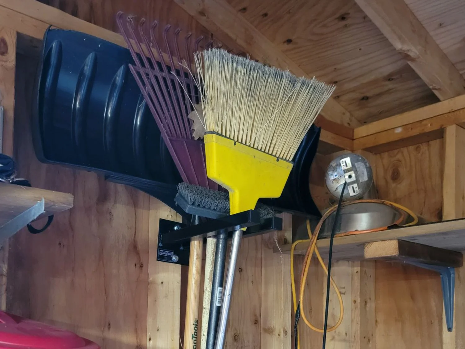 Customer install with 6-inch Double Prong Tool Rack organizing brooms, shovels, and yard tools inside a wood-frame shed
