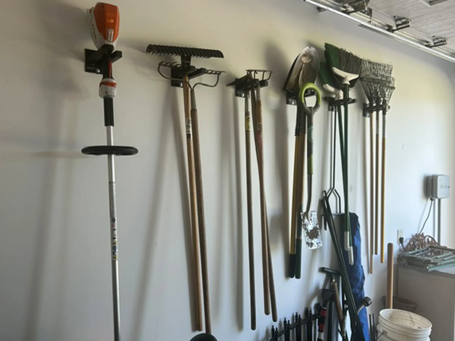 Customer install featuring six 6-inch Double Prong Tool Racks in a Michigan garage holding yard tools, snow shovels, and rakes