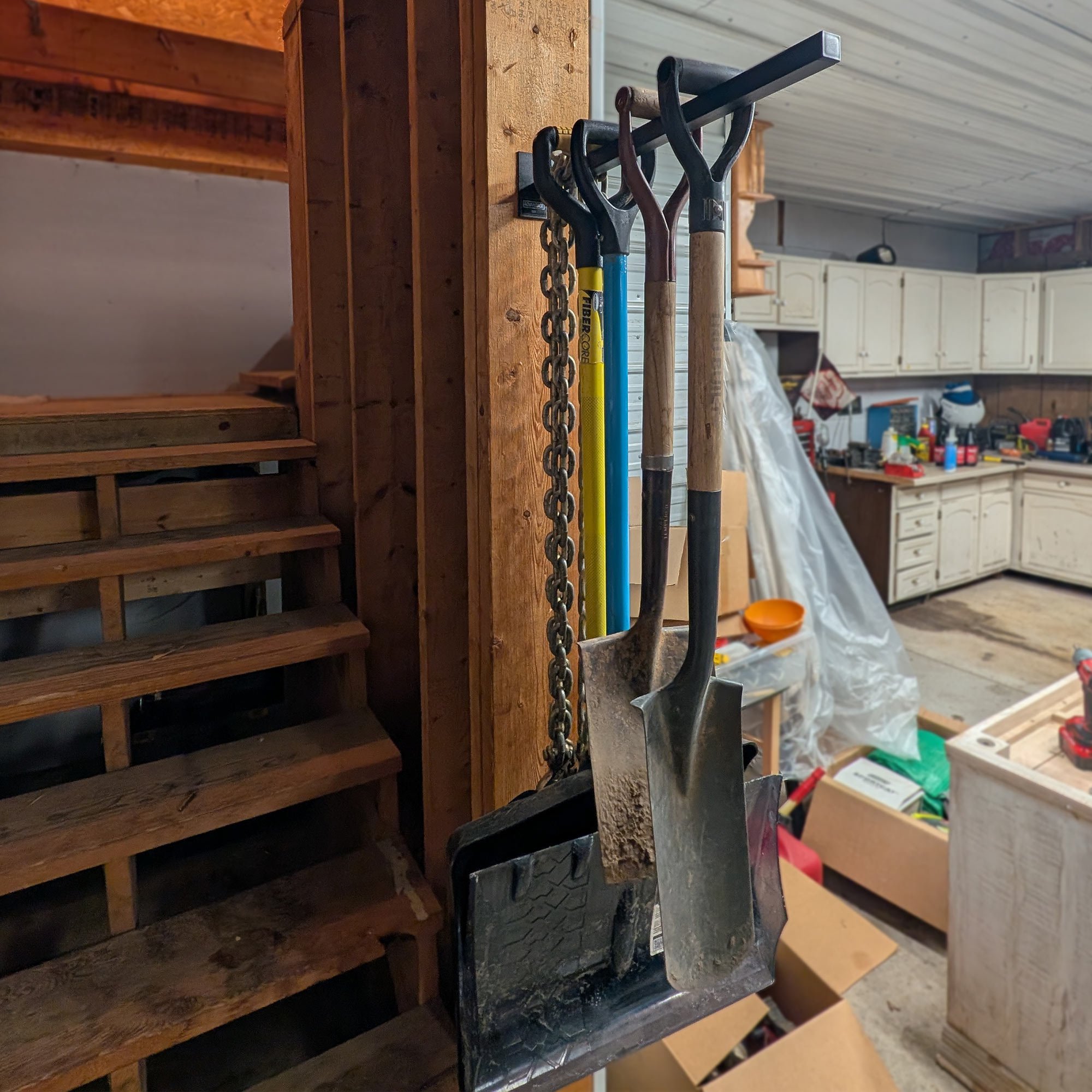 20" Single Prong Tool Rack in satin black powder-coated steel, wall mounted to a garage post holding shovels, a snow pusher, and a chain