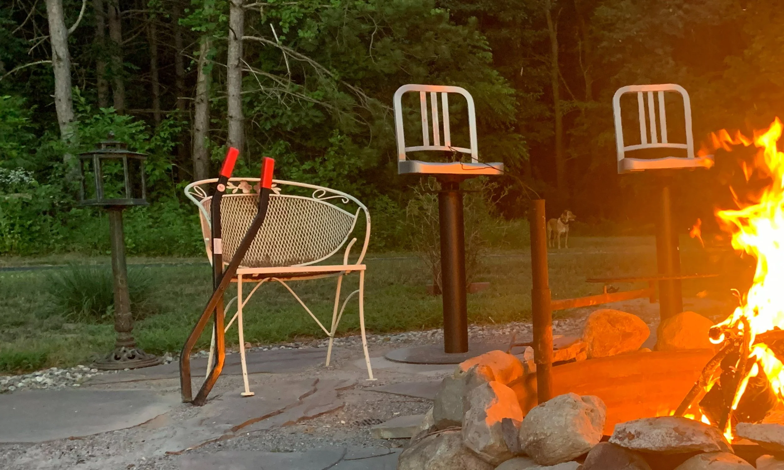 Log Claw Grabbers leaning against chair by campfire for easy firewood handling