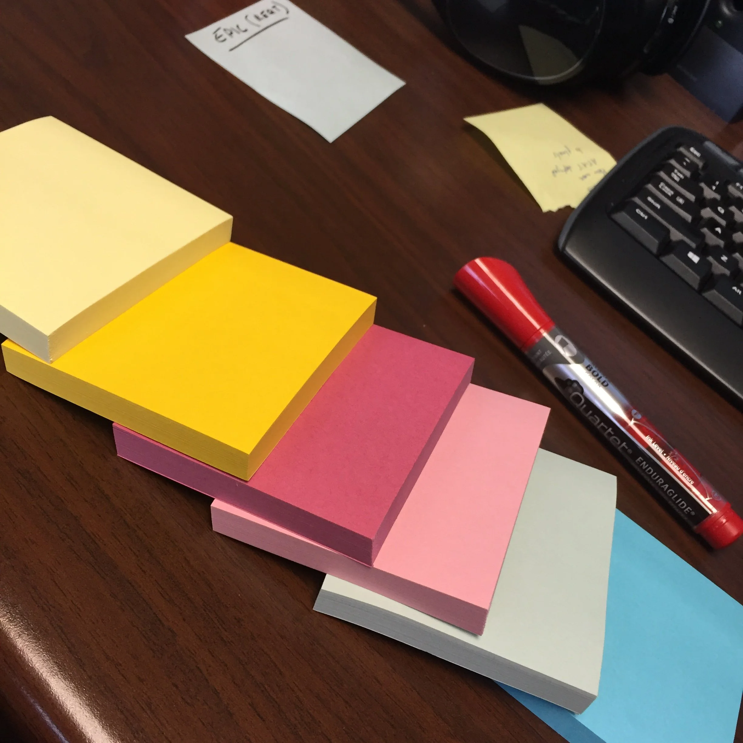  a stack of Post-It sticky notes arranged on a wooden desk 