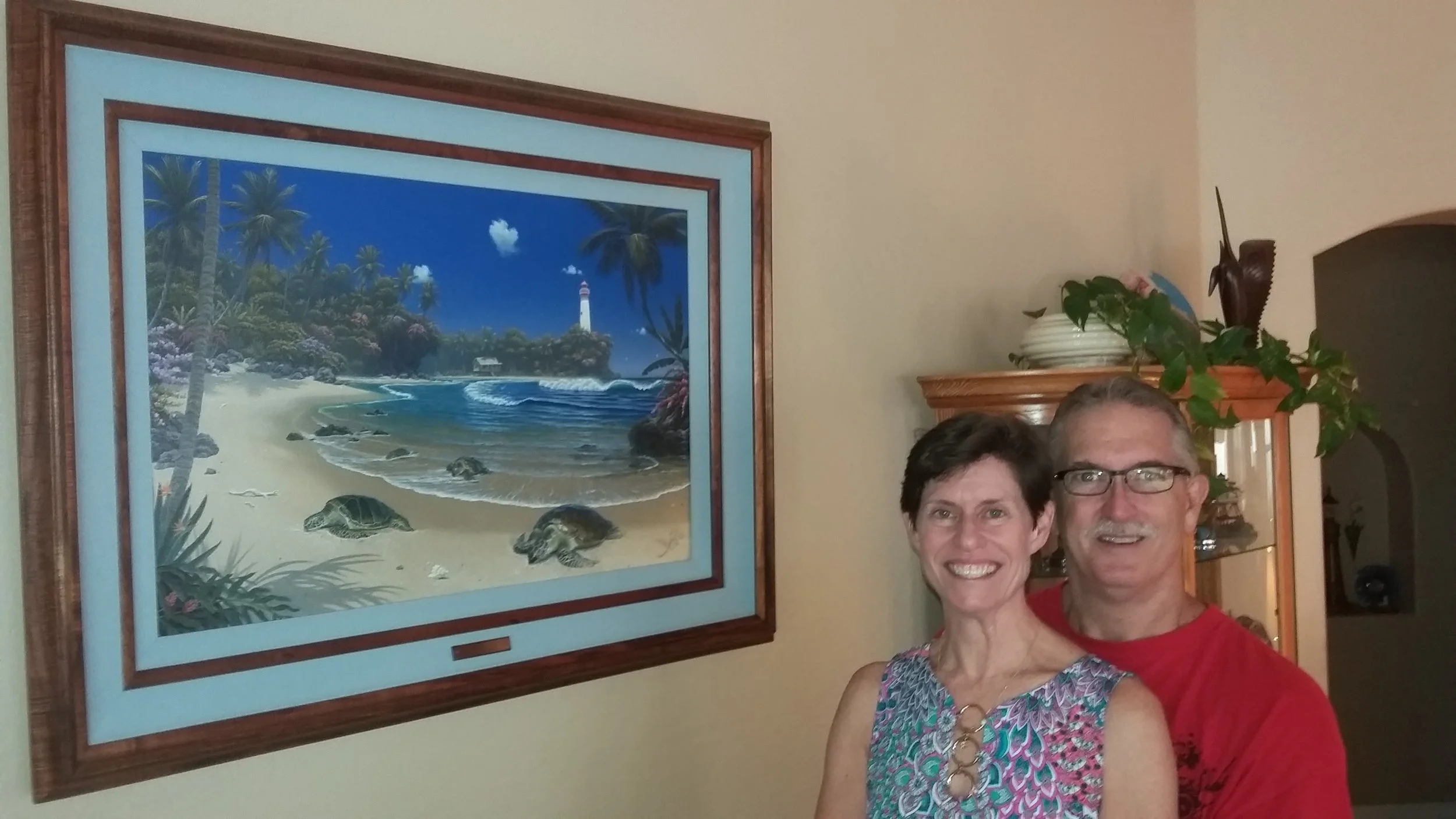 Ron & Leanne Brewster with “Turtle Bay” We were first introduced to Al Hogue’s work on a trip up the west coast in 2007. We fell in love with Tranquility Bay at a shop in Grants Pass Oregon but were unable to purchase the original at that time. We never forgot how much we really like the way he captured the beauty of the Hawaiian Islands. Ron then started a friendship with Al who was living in Hawaii at the time. We love anything to do with sea turtles and purchased from him a piece named “Turtle Adventure”. The artwork is beautiful with the rich colors of the Hawaiian Islands and exquisite frame work of Koa wood. As the years past, Ron kept in touch with Al and exchanged news of our families. In 2018 we decided to have Al do a showcase piece for our home with our beloved sea turtles. He and Ron worked together to create the original, pictured here, “Turtle Bay”. His use of color, light and the way he captures the feeling of the islands are what we love about his work. We will enjoy this truly magnificent piece of art for years to come. R & L Brewster
