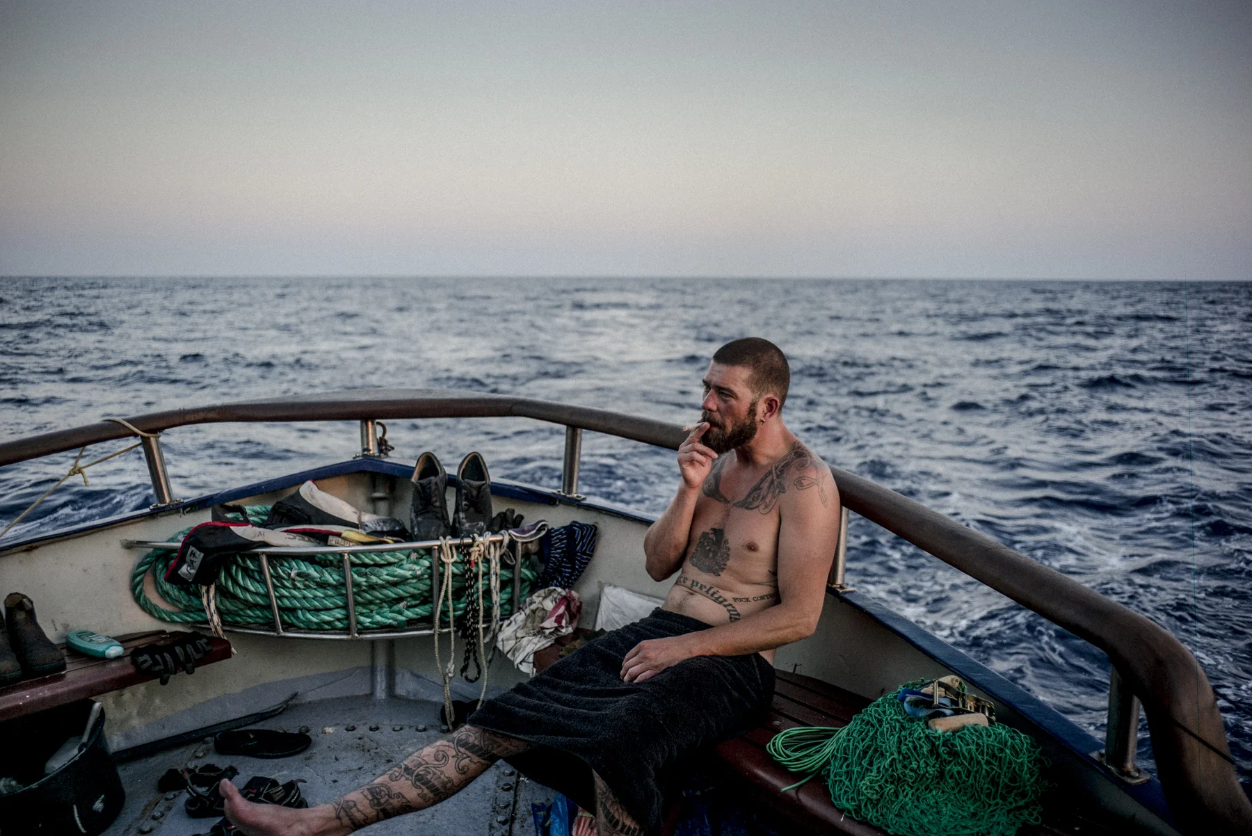Ragino Fagner a crewmember of the Sea-Watch, smokes a cigarette on the vessel's aft deck after a rescue mission.