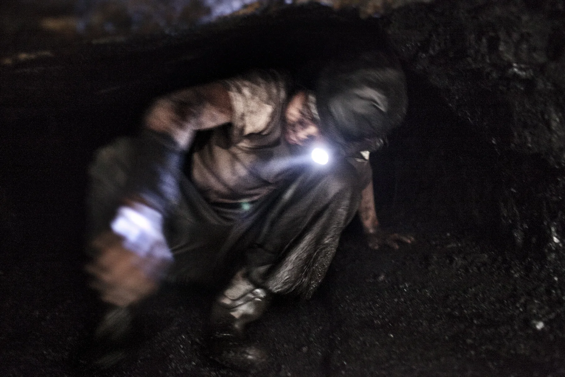 Anil, 15, crawls out of a so called rat hole in a coal quarry in the Jaintia Hills in the state of Meghalaya, India. There are an estimated 5000 mines in the Jaintia Hills. The working conditions are extremely dangerous. According to workers about four people per month die in the mines. The work is often done by minors as young as seven.