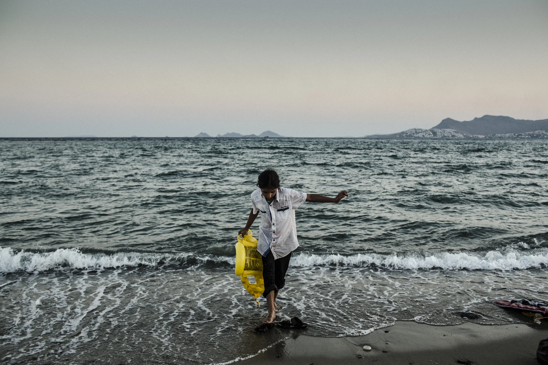 A Pakistani girl plays with a life vest after she and her family crossed from Turkey to the Greek Island of Kos. 