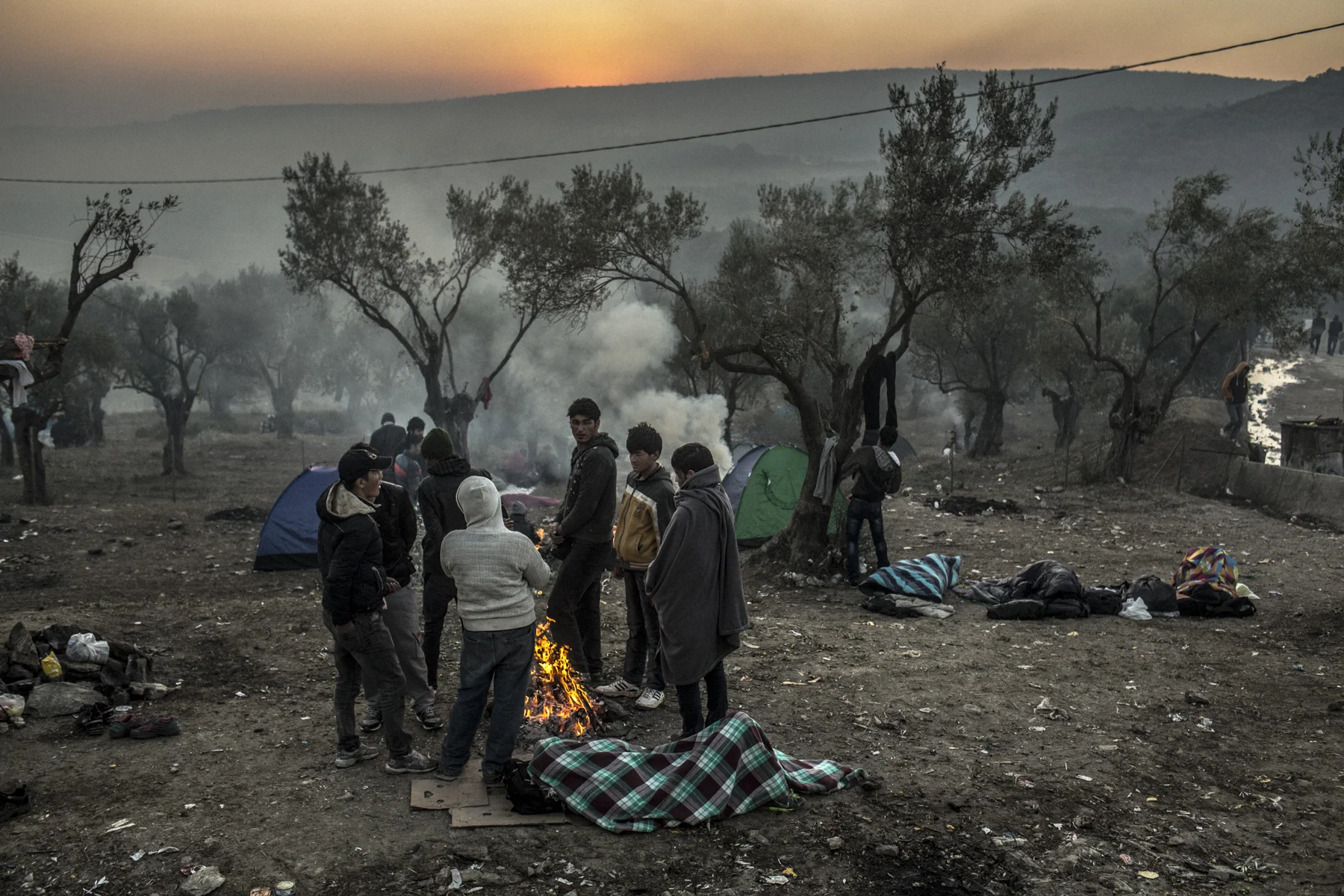 Afghan huddle around a fire in a refugee camp on the Greek island of Lesbos,