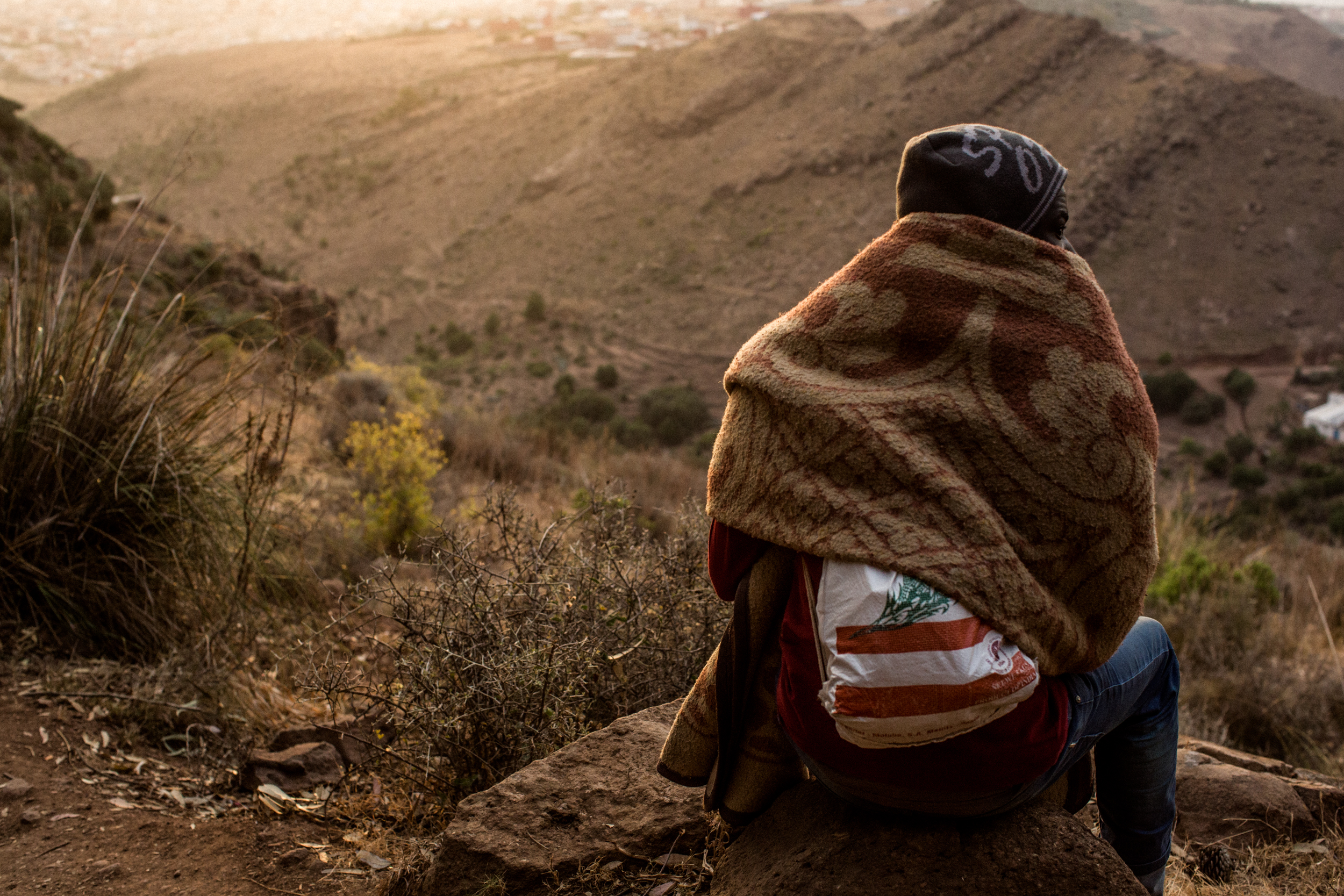 Early morning, a man hides from the Moroccan police as rumors spread that they will raid the camp.