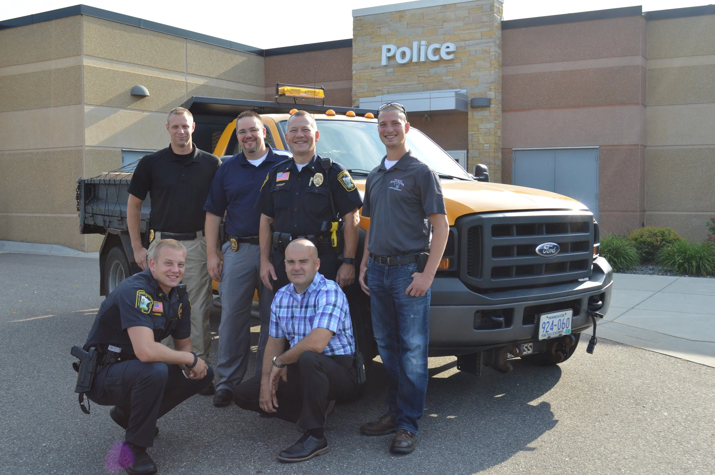 Sauk Rapids Police Officer Charles Wiggum (front, from left) and Sauk Rapids Police Detective Dan Falk; (back, from left) Sauk Rapids Police Officer Nicholas Bogart, Sauk Rapids Police Investigator Sean Gales, Sauk Rapids Police Chief Perry Beise and Benton Soil and Water Conservation District Watershed Technician Travis Janson stand in front of the Sauk Rapids Police Department Aug. 8. The officers prepared boxes of prescription medication for transport to the Pope/Douglas Solid Waste Management facility in Alexandria. Photo Credit to Benton County News