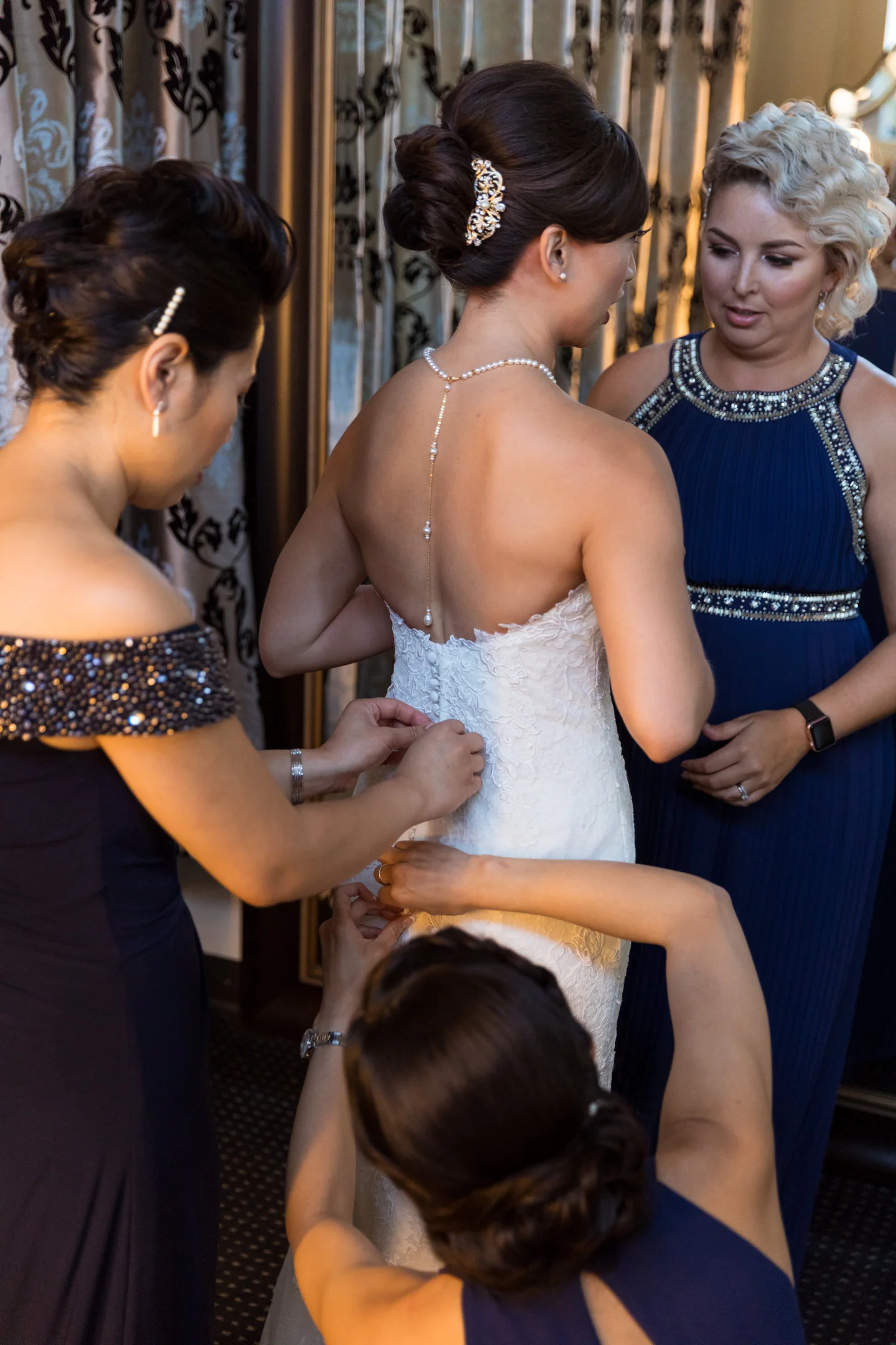Bridesmaids Helping Bride into Wedding Dress