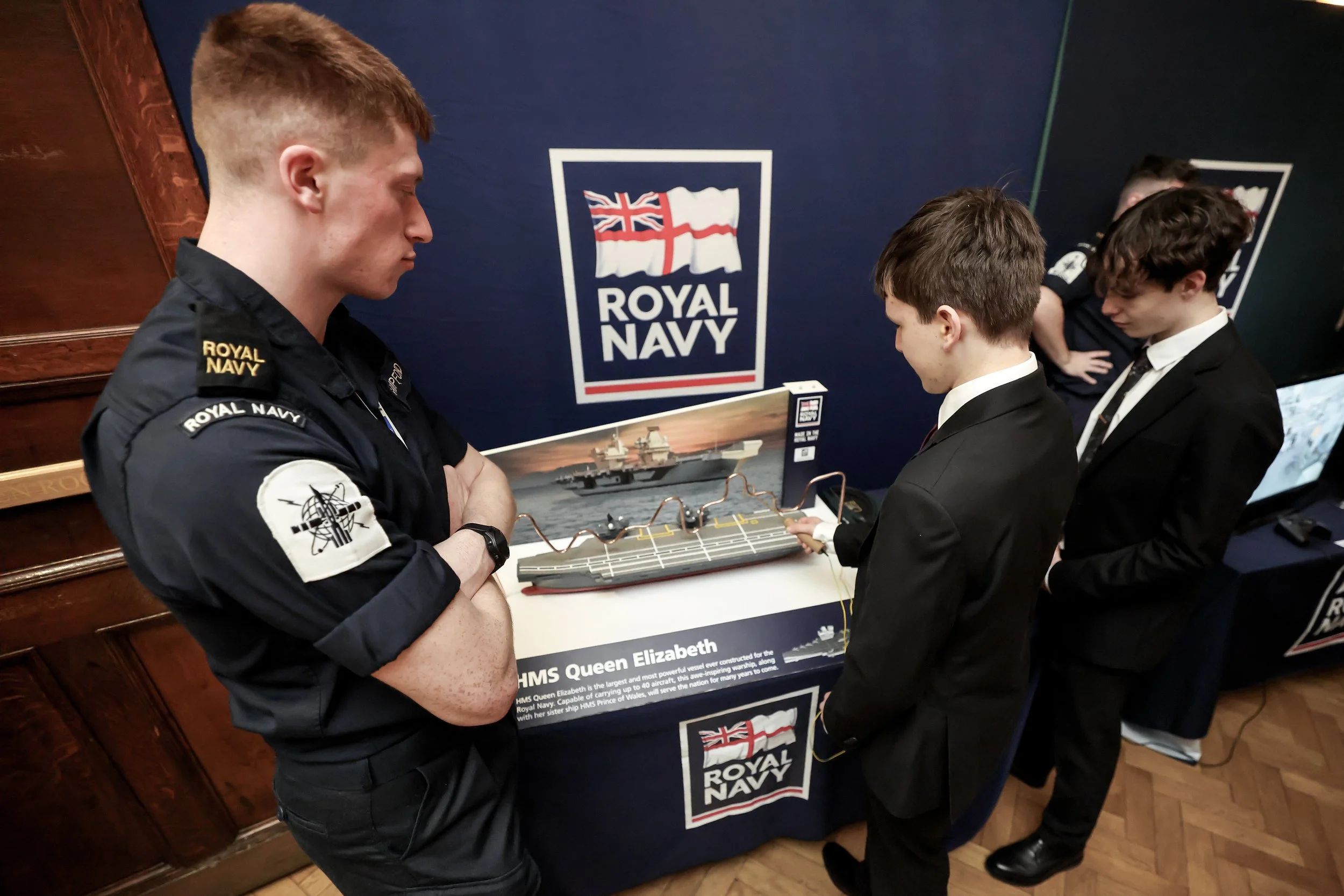 Man in Royal Navy uniform standing in front of an employer stand speaking with two UTC Portsmouth students.