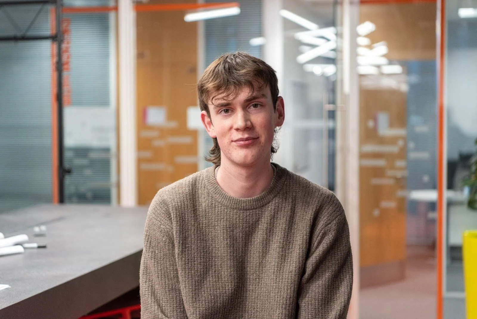 Image of a UTC Portsmouth alumni in front of a glass office.