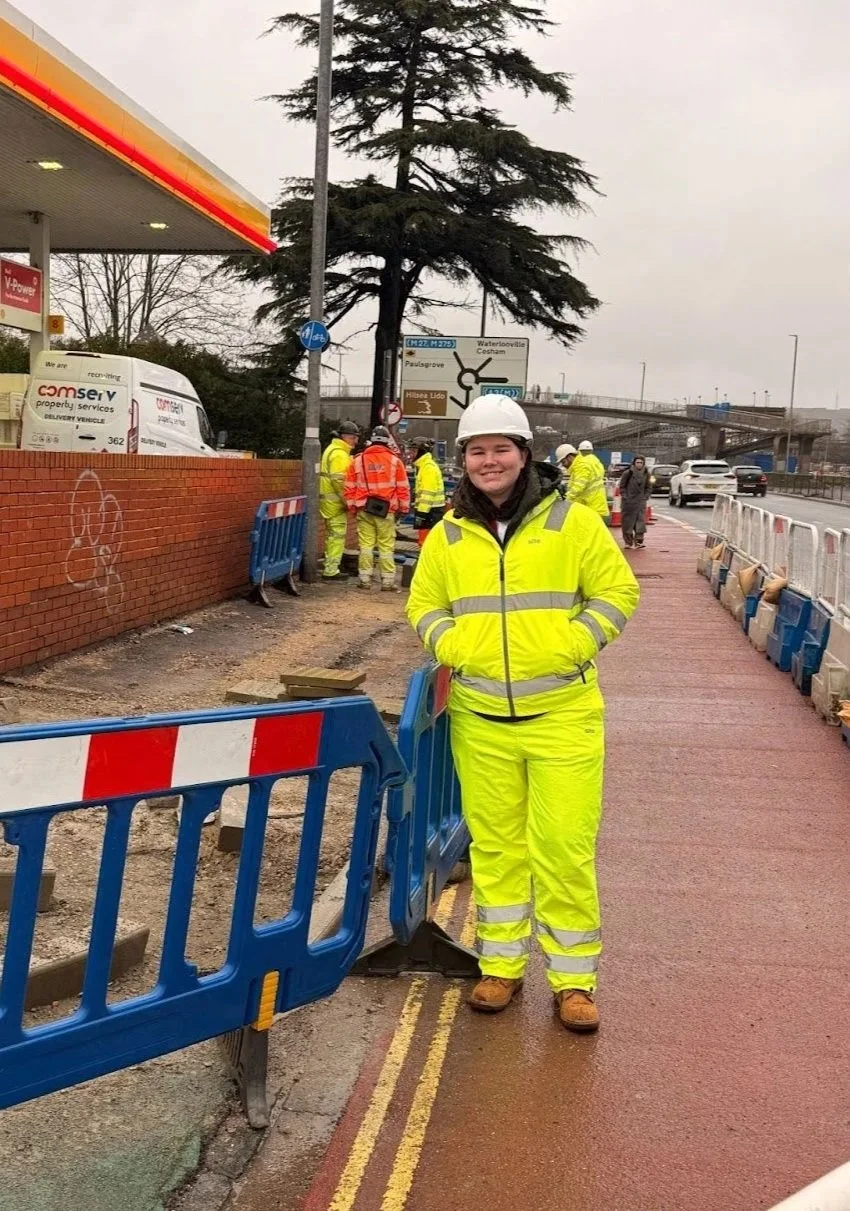 UTC Portsmouth Alumni Student standing in hi-vis workwear in front of a worksite.