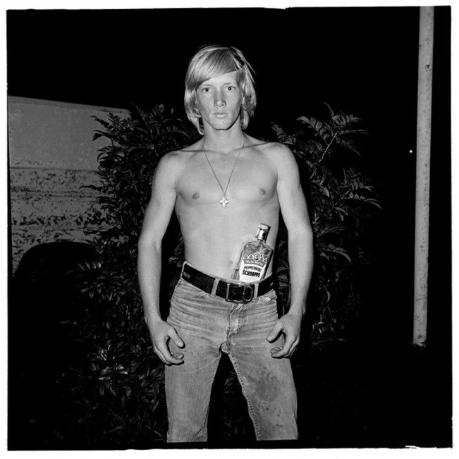 Black-and-white Bill Yates portrait from Sweetheart Roller Skating Rink showing a shirtless young man in jeans posing with a bottle of peppermint schnapps, used as visual inspiration for More Salt, More Acid.
