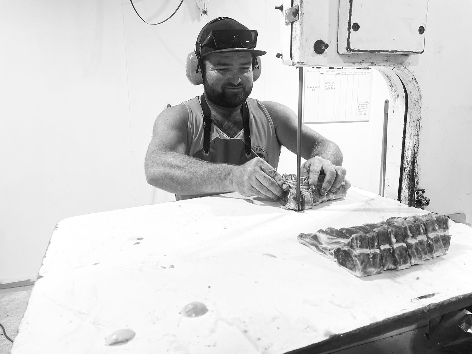 Butcher cutting chops from a sheep carcase with a band saw