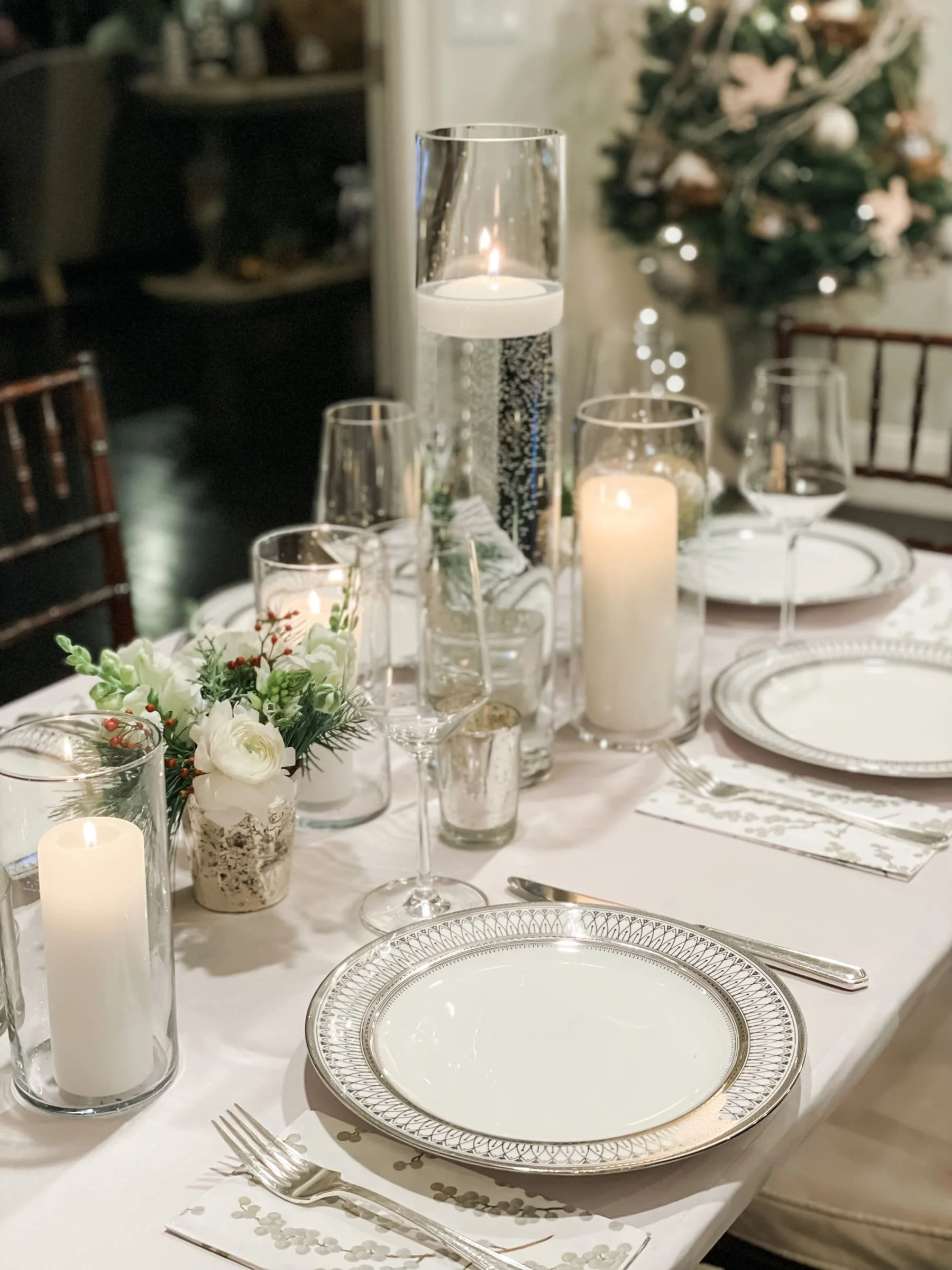 christmas dinner place settings white china plates pillar candles in glass hurricanes