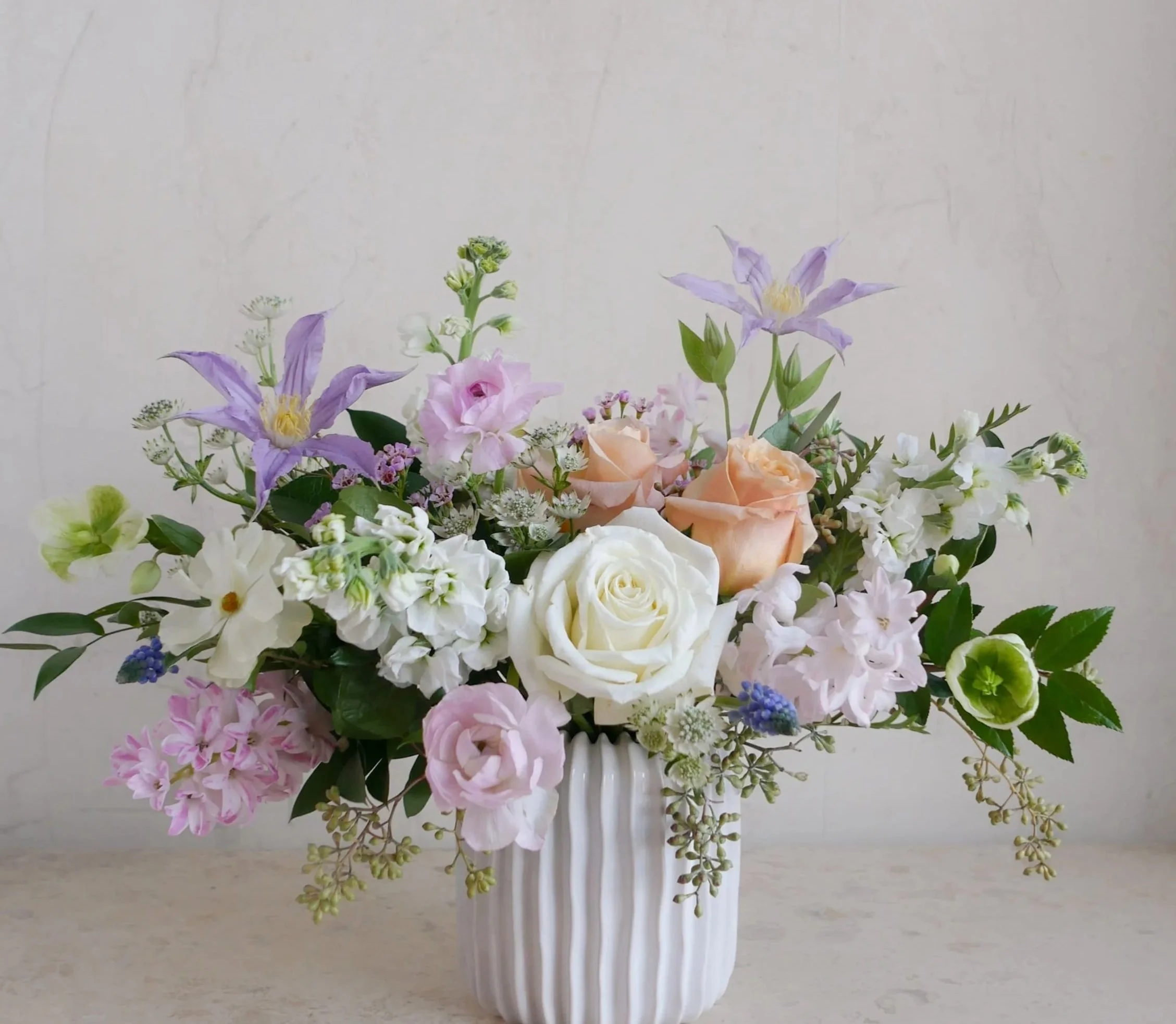 spring floral arrangement pale pink white peach roses purple clematis flowers