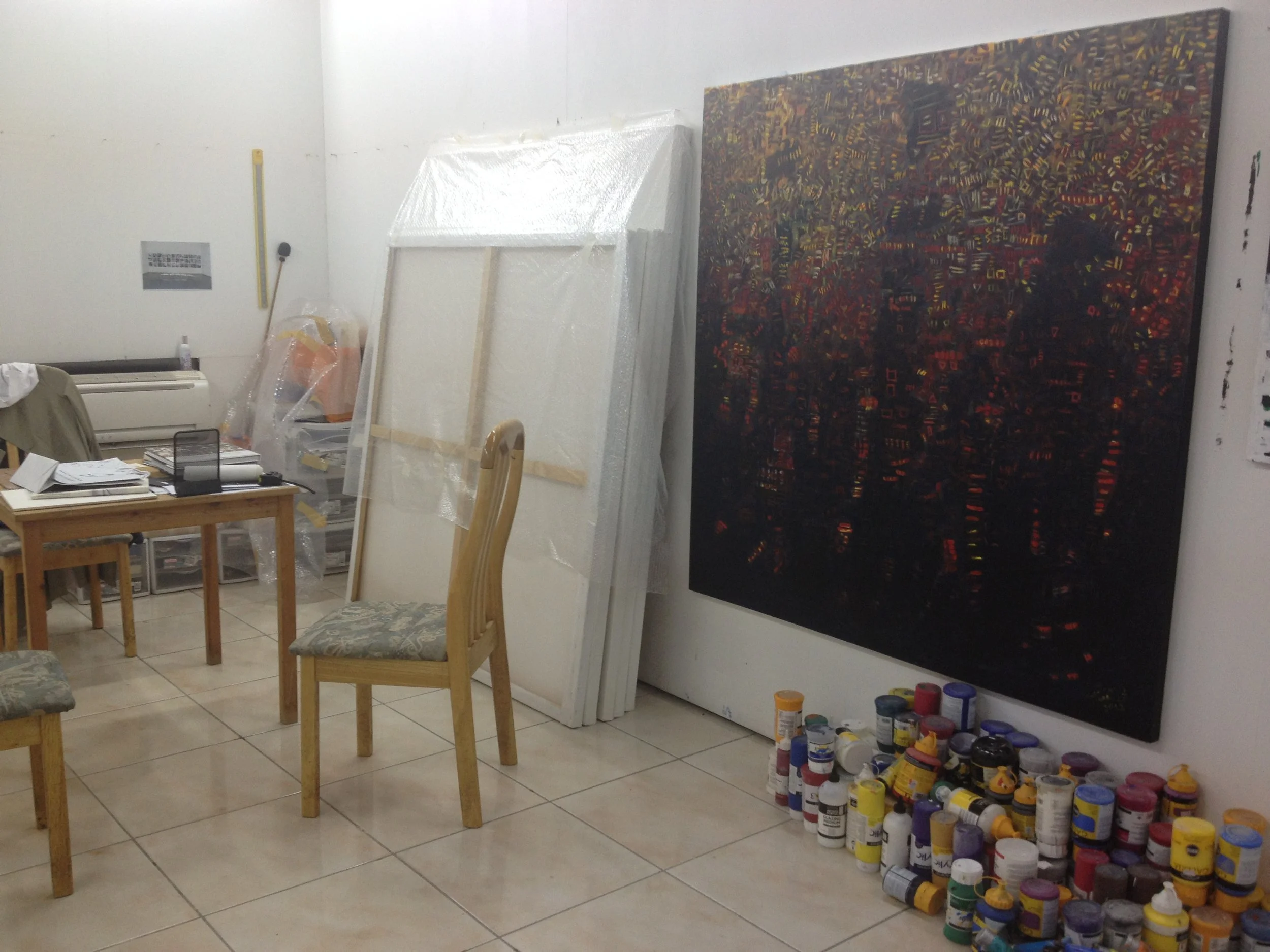 Paints piled high and large scale paintings at Mohammed Al Qassab's studio
