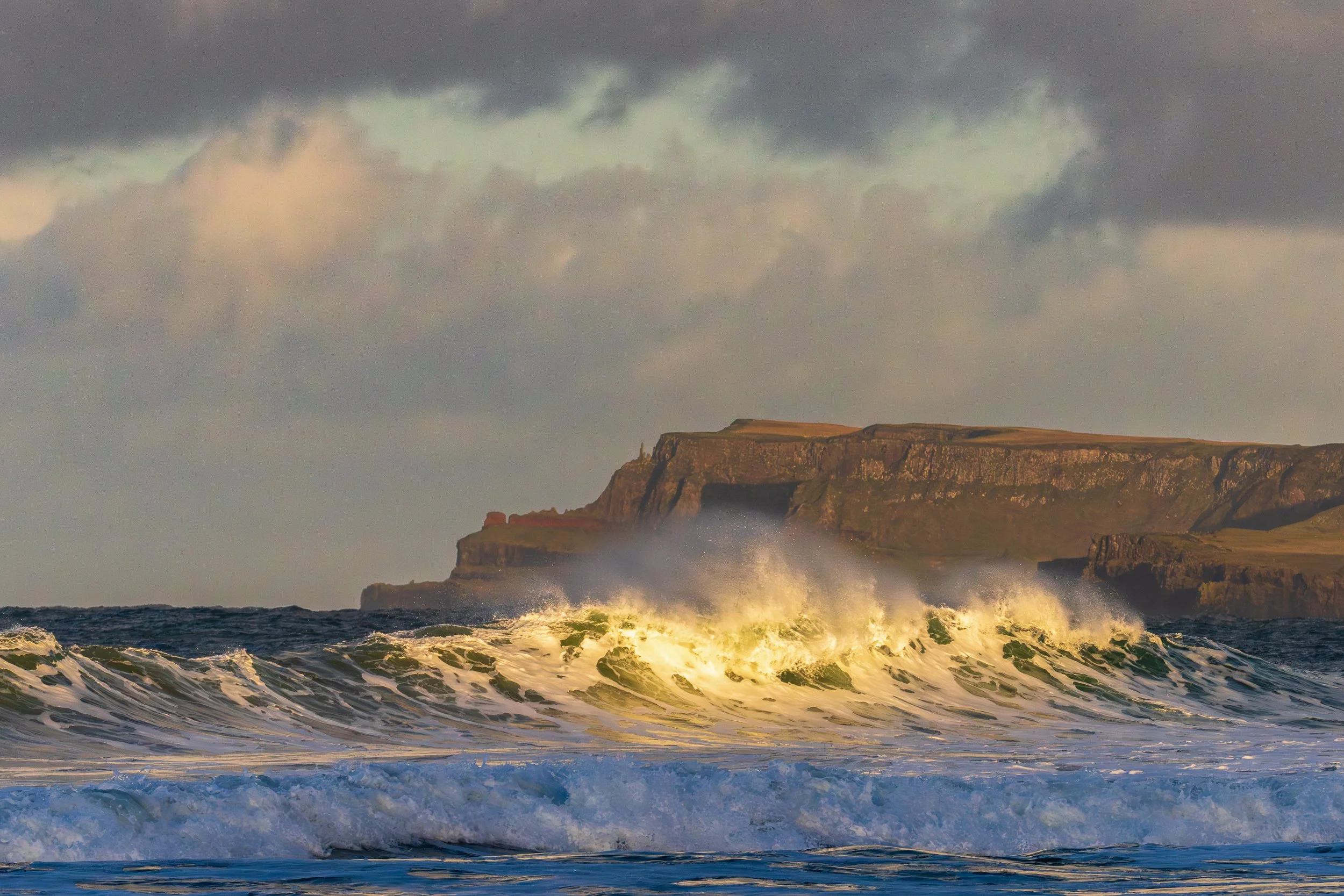 A wave catches the last of the light on the Causeway Coast