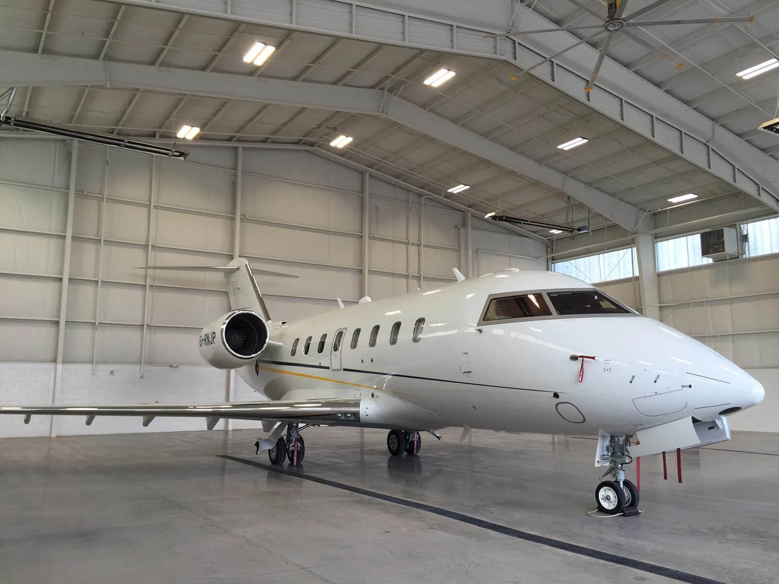 Small jet liner, parked inside a vacant hangar