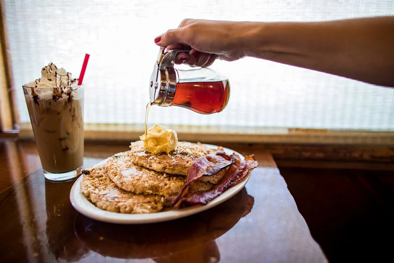 pancakes-being-covered-with-syrup-next-to-a-chocolate-shake.jpg