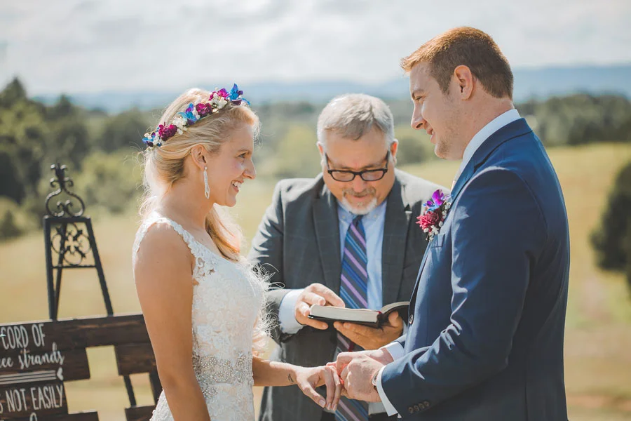 Bride Bri smiles at husband Matthew as they exchange vows and rings during their July wedding ceremony. Eades-Swarm Wedding, page 66 of bridebook 2019. Image by Olivia Diane Photography.