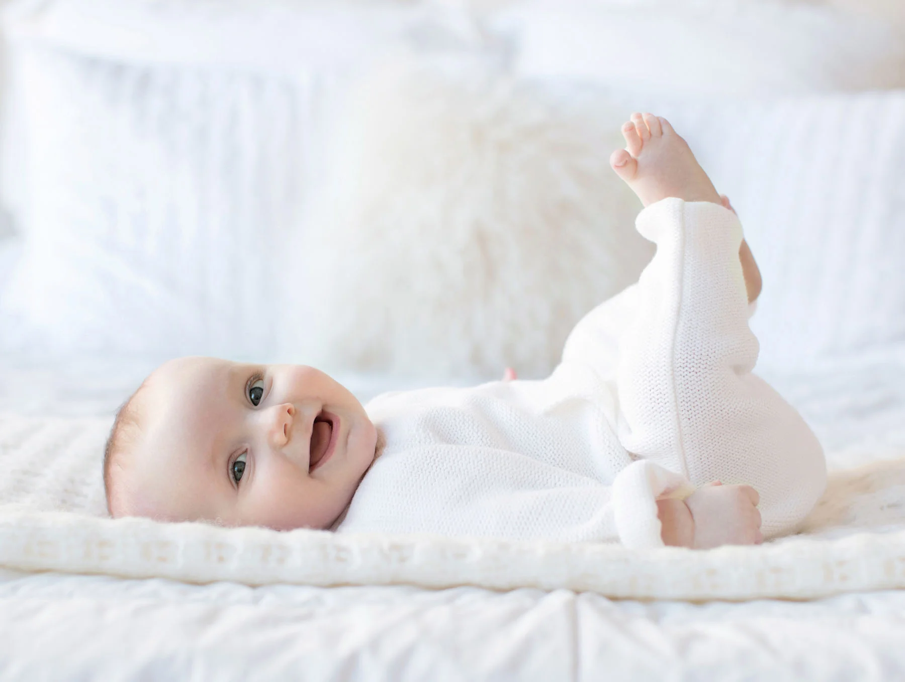 smiley_baby_in_white_on_bed_six_months.jpg