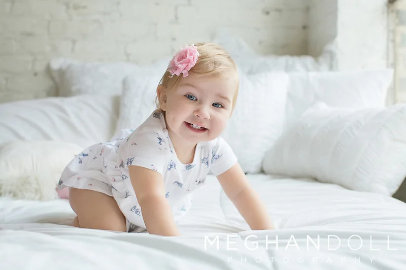 one-year-old-girl-smiles-on-bed