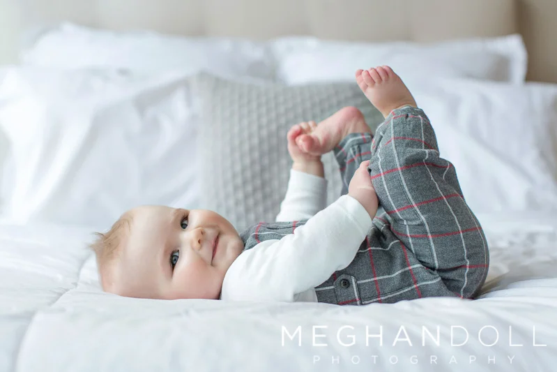 six-month-old-boy-plays-with-his-toes-on-bed