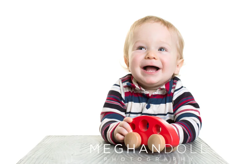 one-year-old-boy-in-stripes-plays-with-red-car