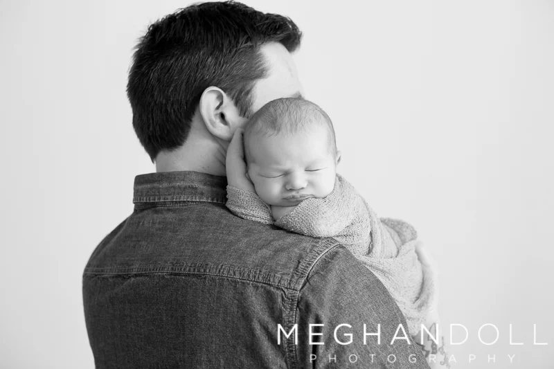 dad-holds-newborn-son-over-his-shoulder