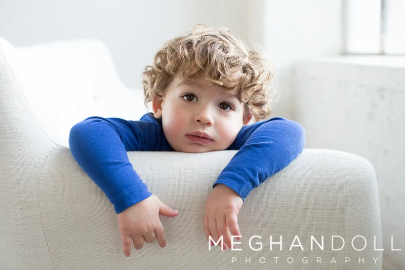 sweet-two-year-old-boy-hangs-over-side-of-couch