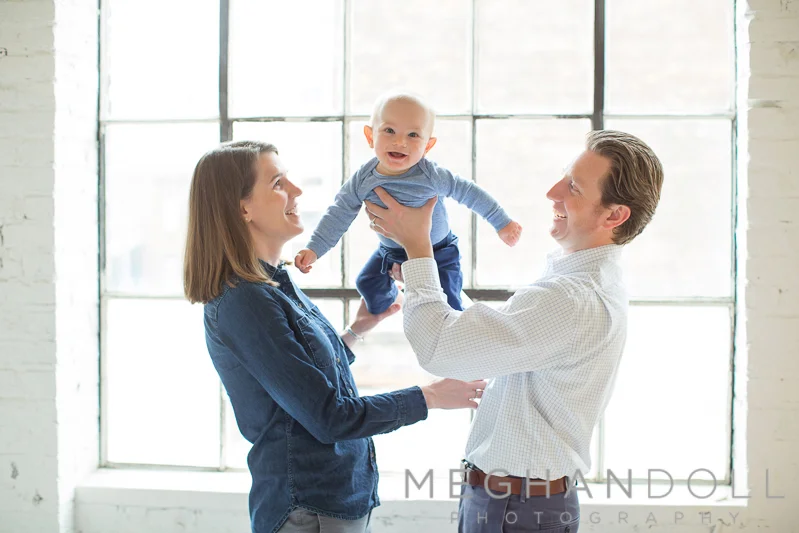 six-month-old-boy-plays-with-parents-by-window