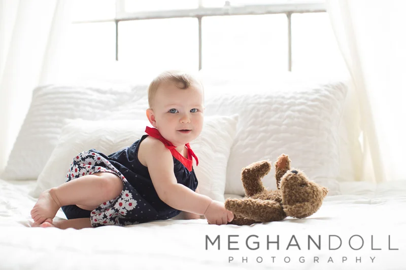 baby-girl-plays-with-teddy-on-bed
