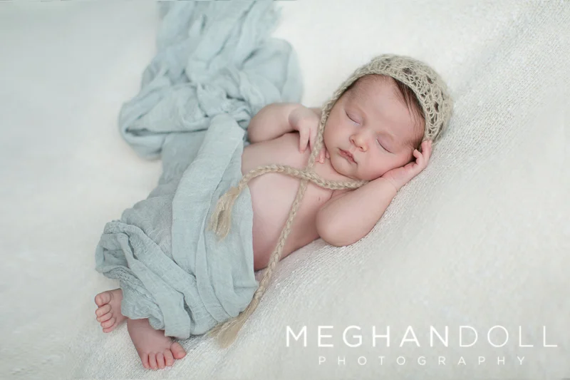 sleepy-newborn-boy-in-light-blue-and-tan-hat