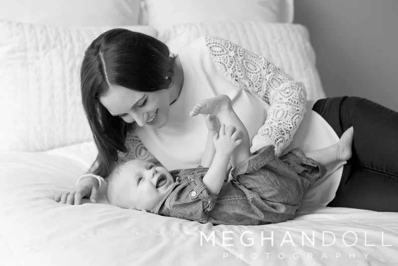 mom-plays-with-six-month-old-baby-on-white-bed