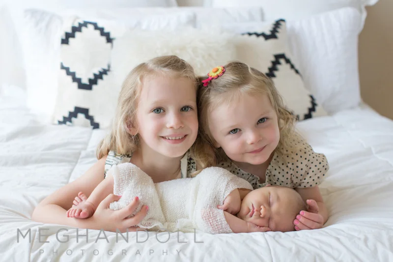 sisters-on-bed-with-baby-brother