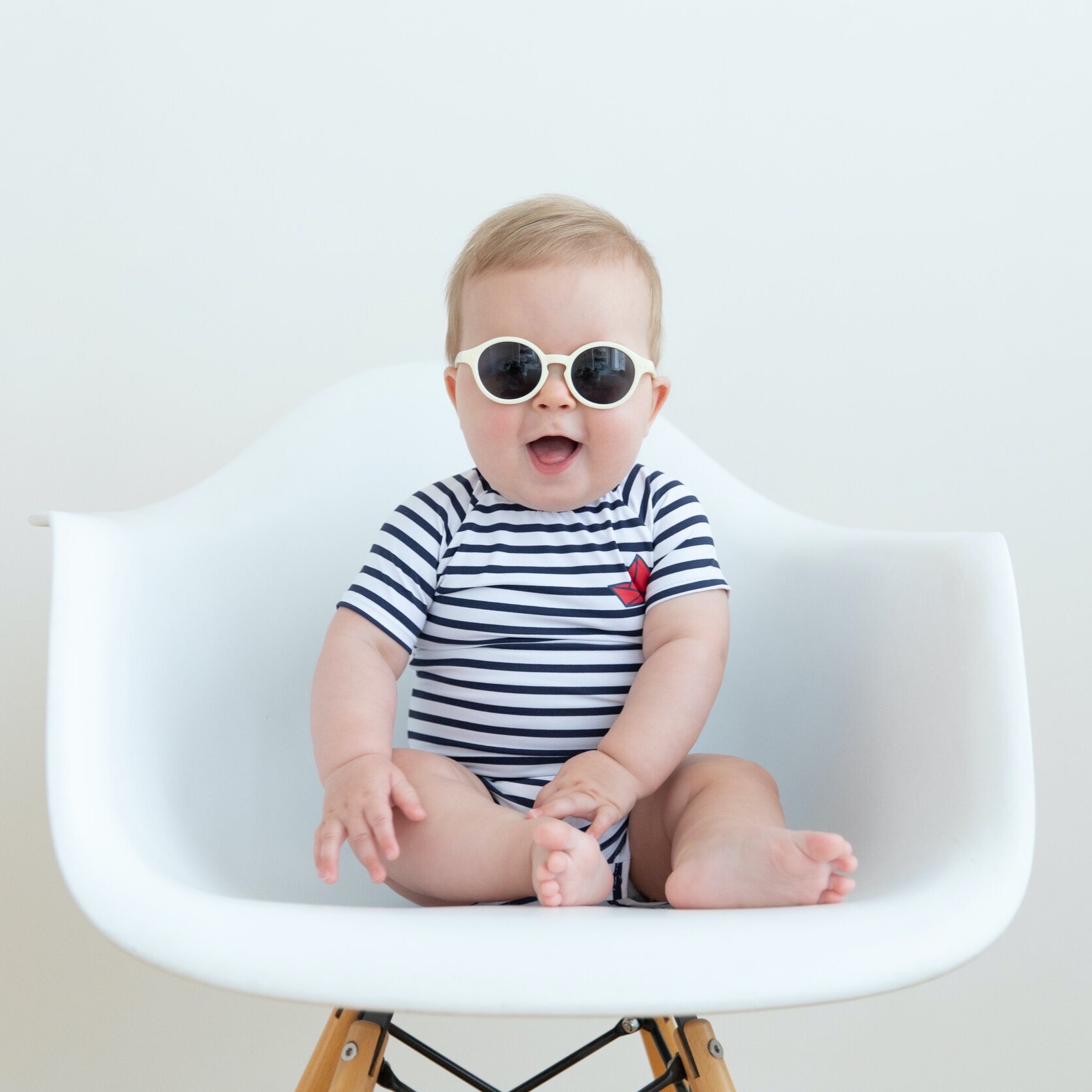 Baby boy wearing sunglasses and sitting in a chair for his six month session.