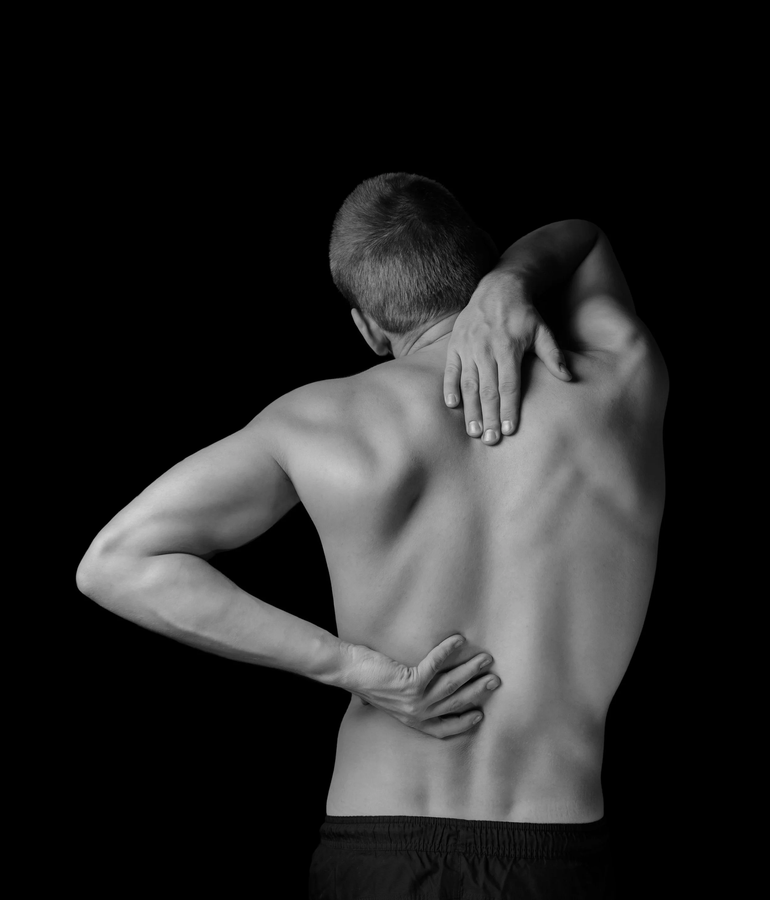 man rubs his back to indicate back pain