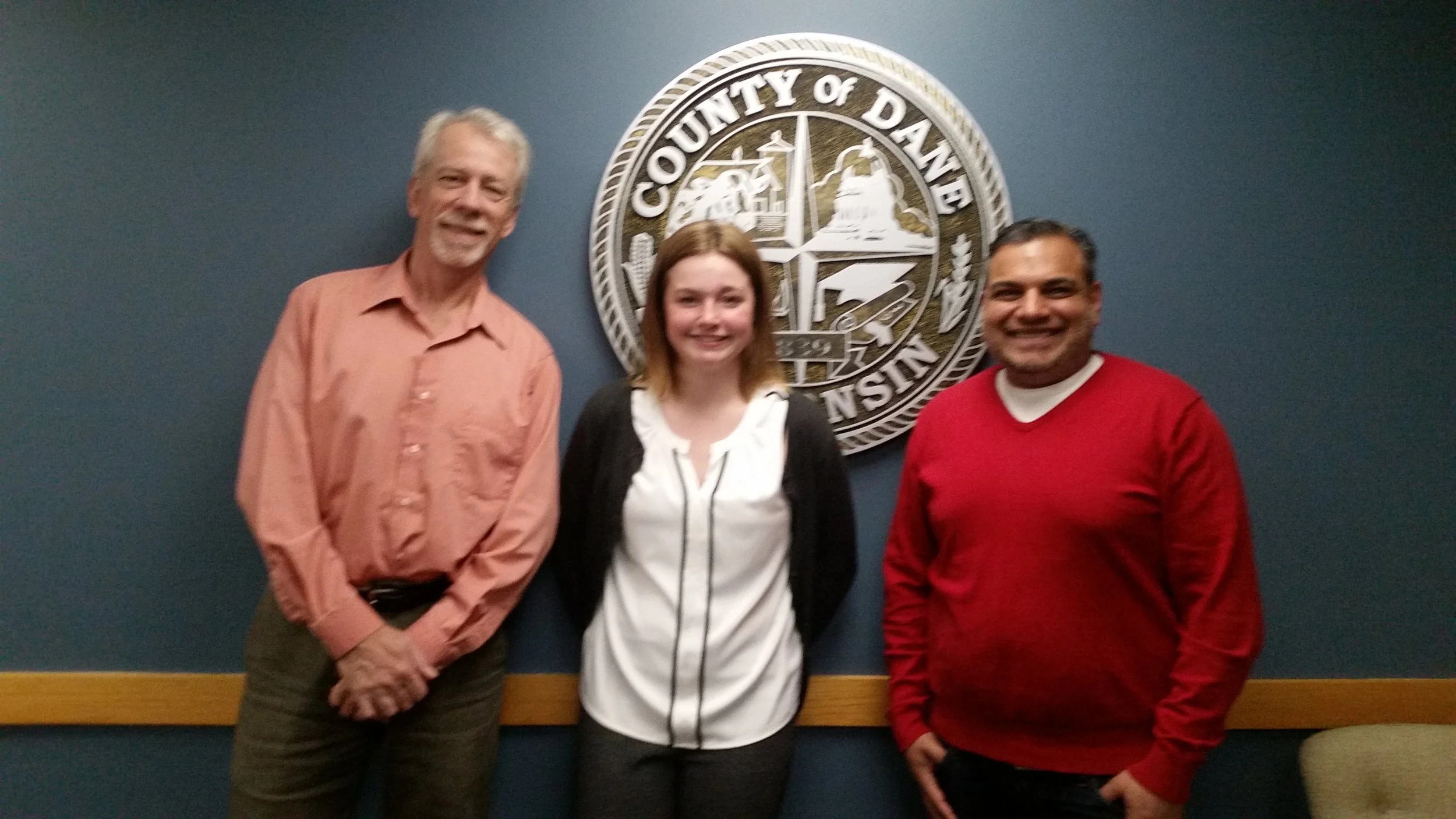 Keith, Lily and Yogesh snap a photo in front of the County Seal after a productive meeting.