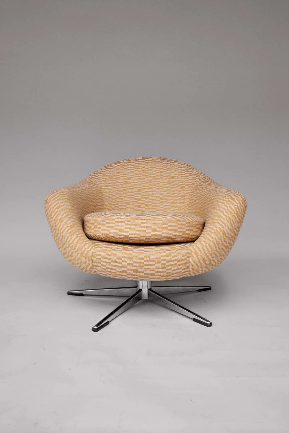 Front view of 1960s low swivel chair upholstered in BUTE FABRICS CLAN FABRIC CF1116 on grey background