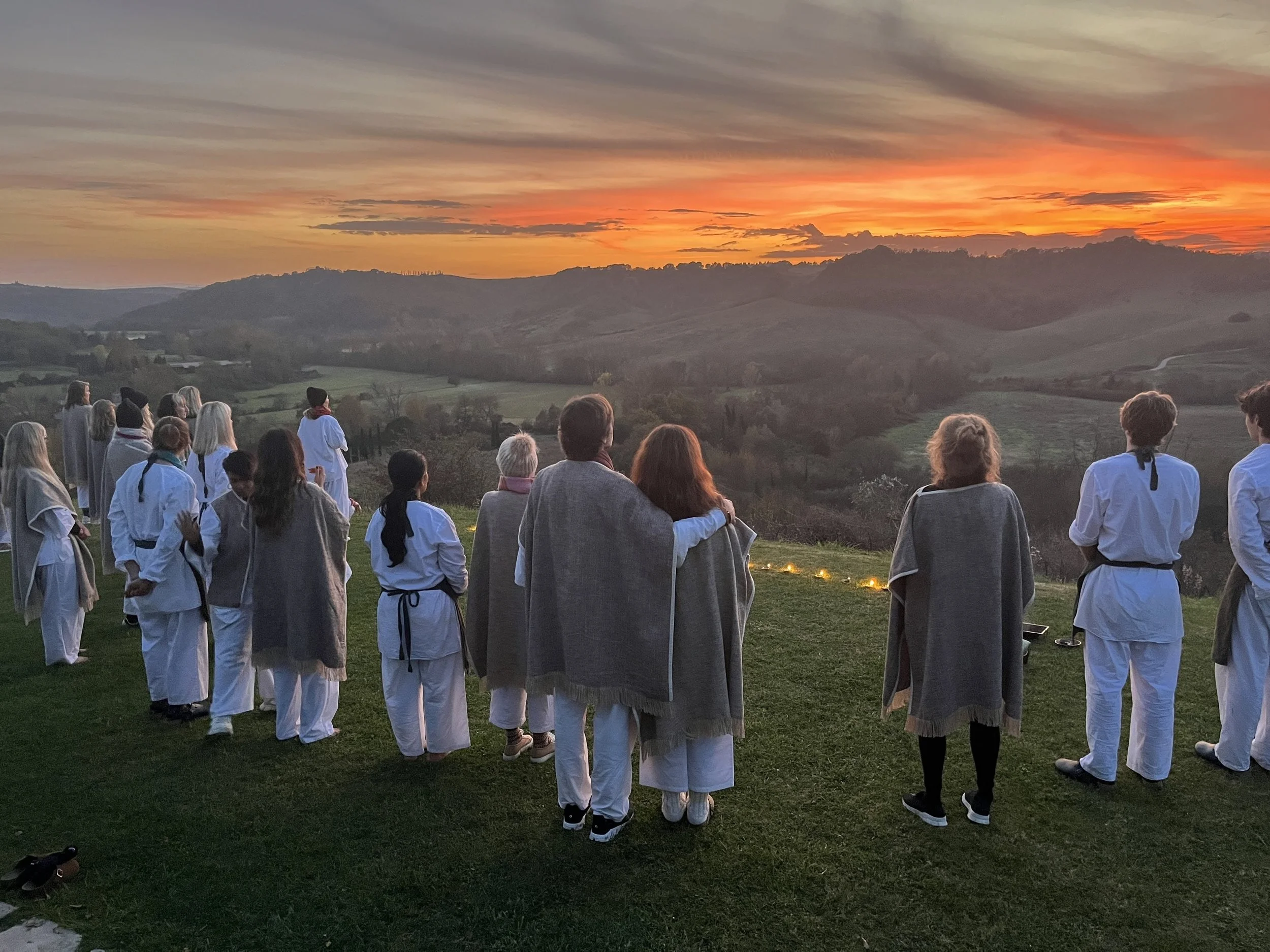 A group of people watching the sunset over mountains and hills