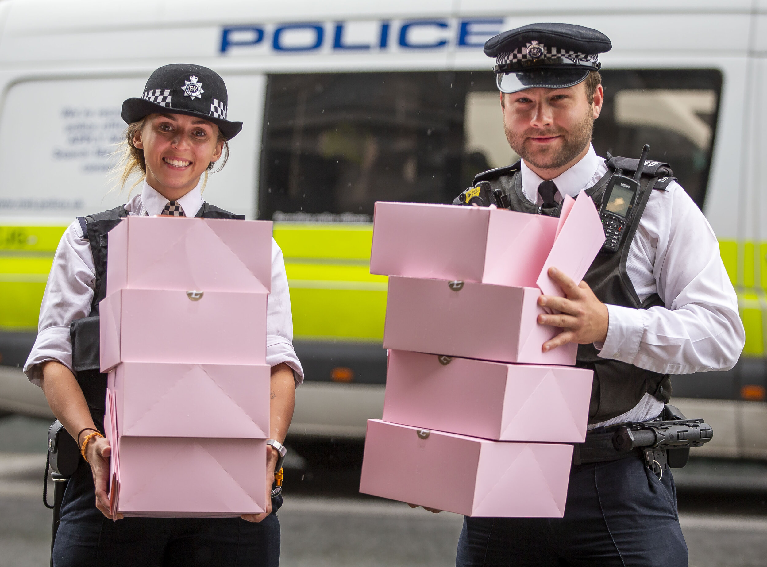 Two police officers holding several Langham afternoon boxes
