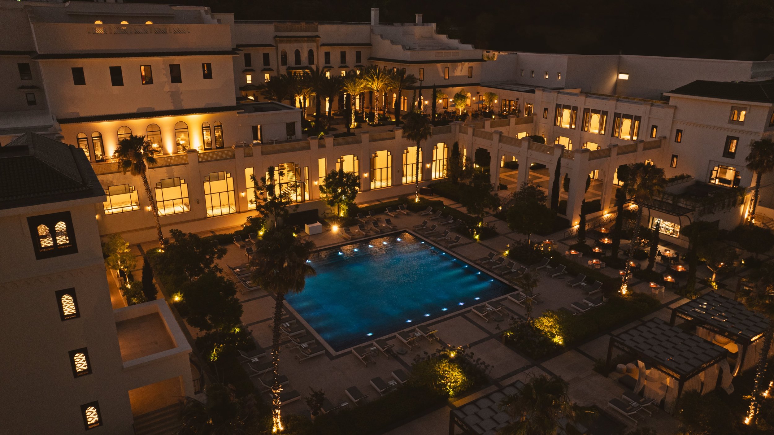 An aerial shot of the Fairmont Tazi Palace at night with the lights on