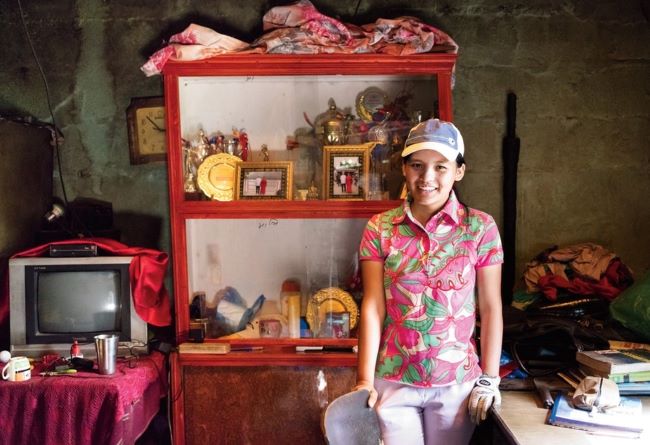 Pratima Sherpa at home in Kathmandu, standing in front of the cabinet in which she stores her trophies Image Credit - . Vladimir Weinstein/Golf Digest