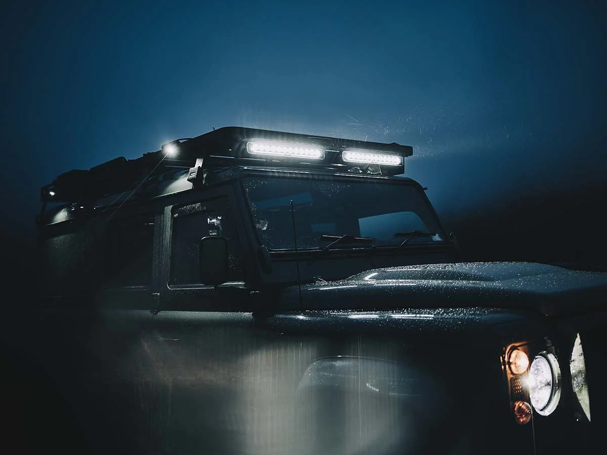 dramatic image of a Land Rover defender, with light bars lighting up the foggy twilight sky travel story by automotive photographer Matthew Lloyd
