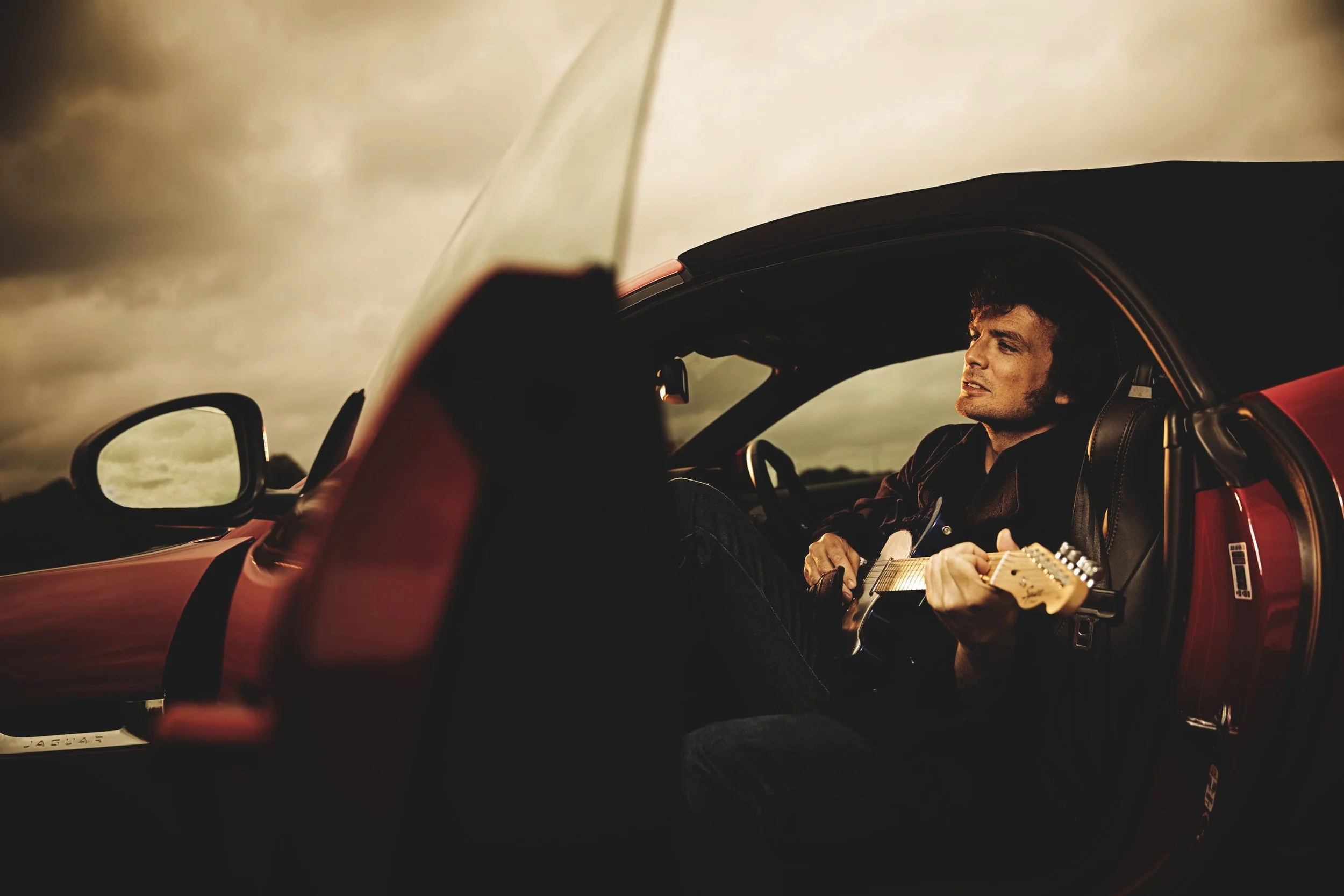 journalist will hodgkinson poses in a Jaguar F-Type by photographer Matthew Lloyd