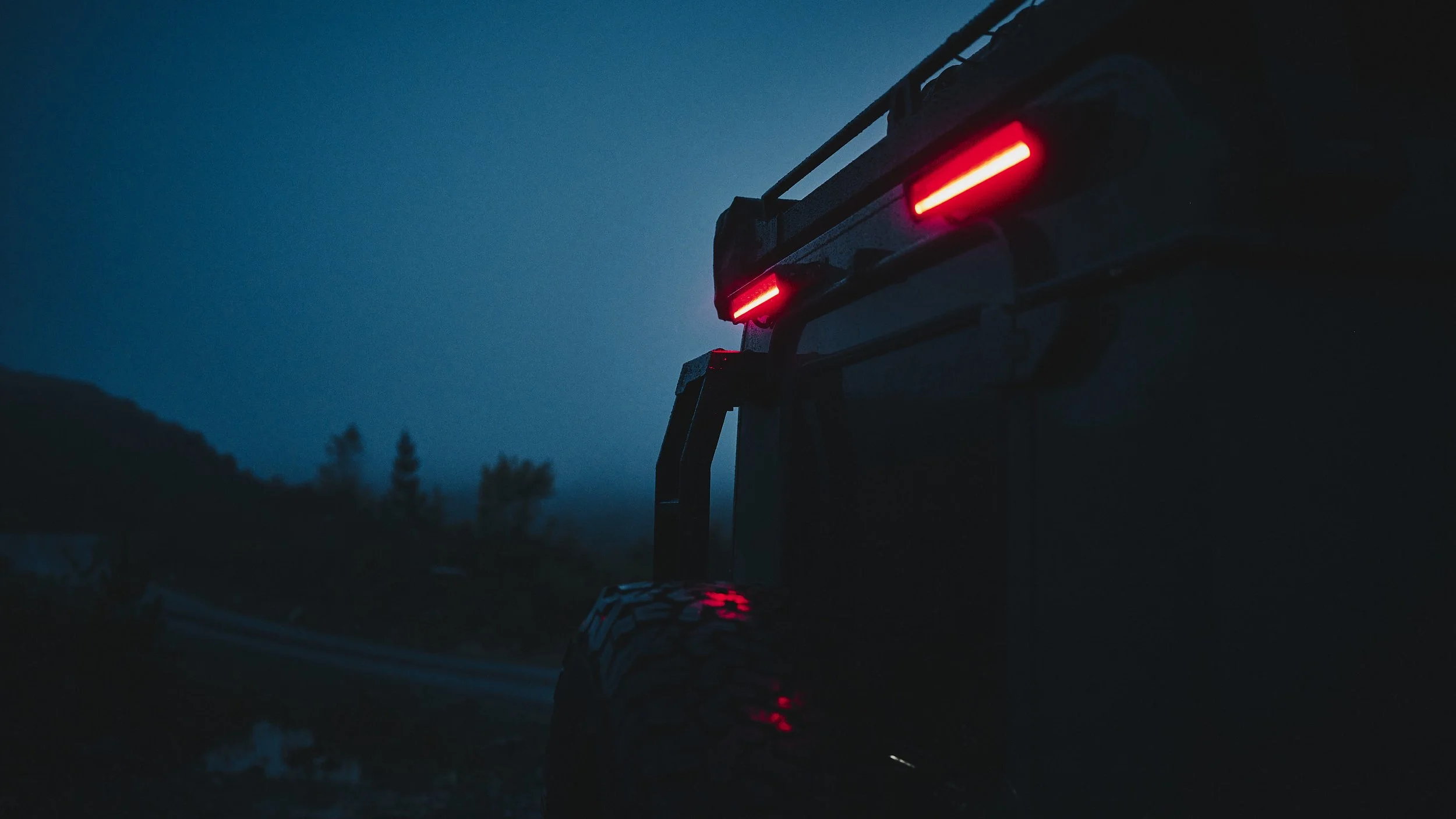 dramatic image of a Land Rover defender, with light bars lighting up the foggy twilight sky travel story by automotive photographer Matthew Lloyd