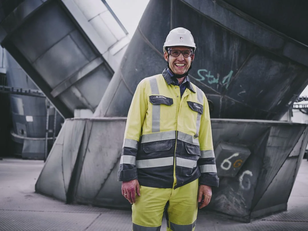 Smiling worker in safety gear and helmet at industrial site