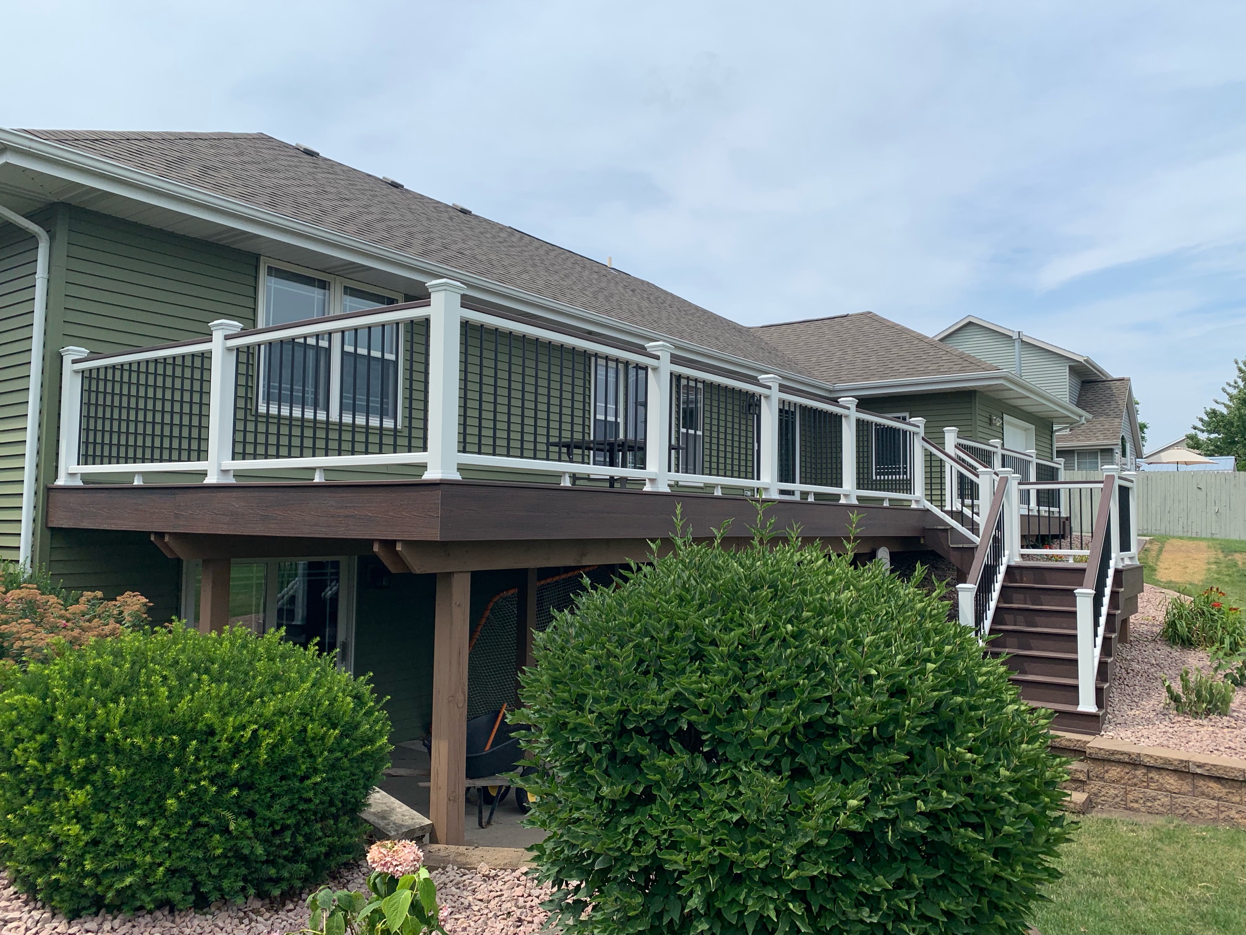 Trex Lava Rock deck boards with white top and bottom rails, Lava Rock drink rail on top of railings, black aluminum balusters and white post sleeves, post skirts, post caps.