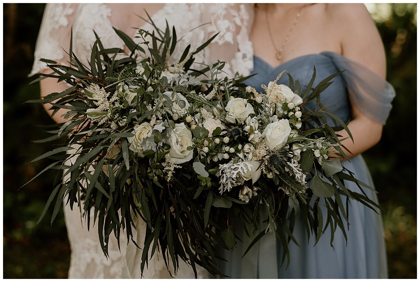 bride with bridesmaids wearing dusty blue long dresses and holding greenery bouquets